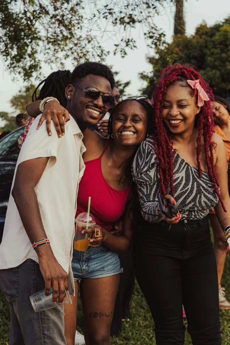Three friends laughing and hugging outdoors